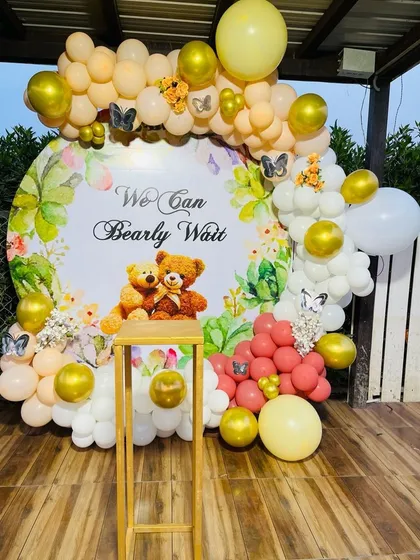 Here is another take on the "We Can Bearly Wait" theme, perfect for an outdoor or terrace baby shower. This setup features a custom printed circular backdrop surrounded by a balloon garland in peach, white, and gold.