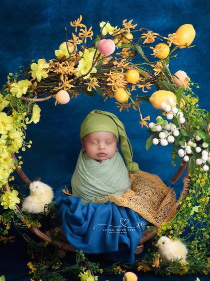 Cherished moments. This little prince, wrapped in green and surrounded by a wreath of yellow flowers and tiny chicks, looks like he's in a fairytale.