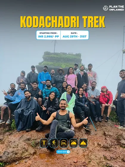 A large group celebrates at the muddy summit of Kodachadri, showing the true spirit of a monsoon trek.