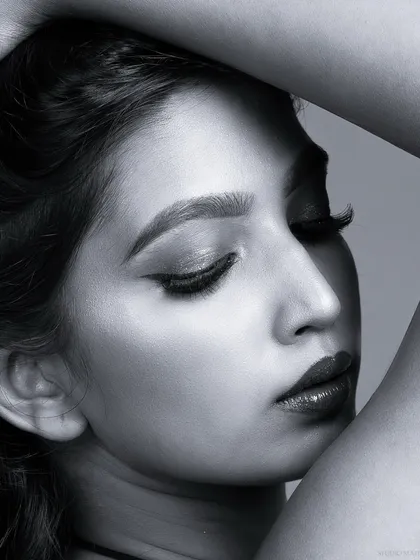 A close-up monochrome beauty portrait. The black and white format emphasizes the contrast of the winged eyeliner and the soft texture of the skin.