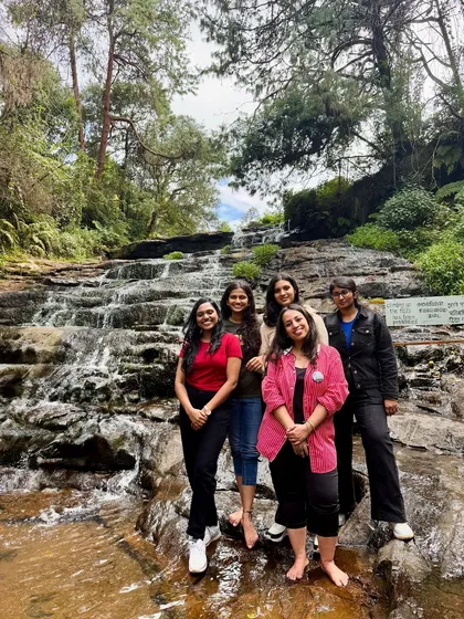 A group of friends posing by a beautiful tiered waterfall in Kodaikanal.
