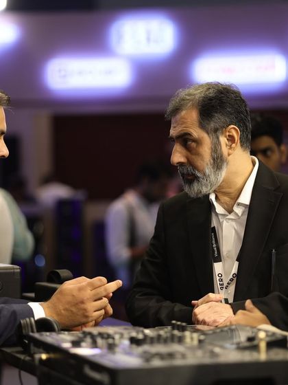 High-level networking in action, as industry veterans discuss business over a display of professional audio equipment.