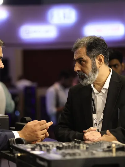 High-level networking in action, as industry veterans discuss business over a display of professional audio equipment.