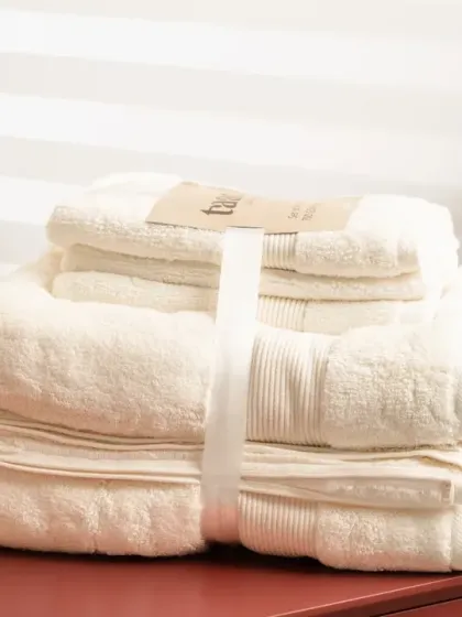 A set of off-white towels in the same modern bathroom setup. We ensure the color accuracy of products is maintained in the final images.