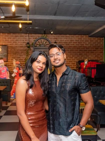 A stylish couple posing inside the pub. The checkered floor and brick wall create a great backdrop.