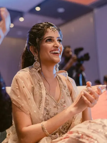 A radiant smile from the bride-to-be. Her makeup features a soft, diffused eyeshadow and a natural lip, creating a timeless and elegant sangeet look.