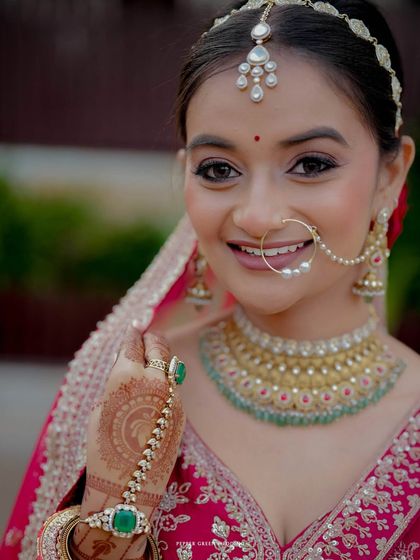A beautiful close-up of the North Indian bride, highlighting her intricate nath (nose ring), matha patti, and stunning jewelry.