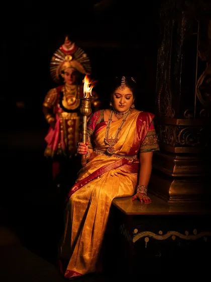 A moment of quiet reflection from the "Belaku" shoot, where the subject is seated with the torch, surrounded by darkness.