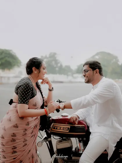 A couple shares a lighthearted moment, leaning against a vintage Yezdi motorcycle in Mysore. This shot combines personal interests with a classic pre-wedding theme.