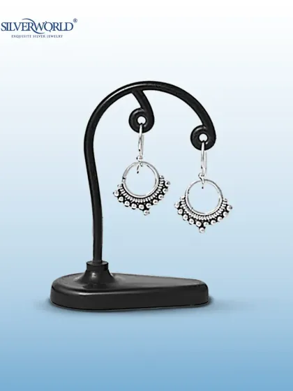 These vintage-inspired half-moon or 'chandbali' style earrings feature delicate silver beadwork. They are displayed on a stand to show their unique shape and craftsmanship.