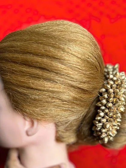 A side view of a classic bridal bun, adorned with a traditional golden hair accessory. This is a timeless and elegant choice for any bride.