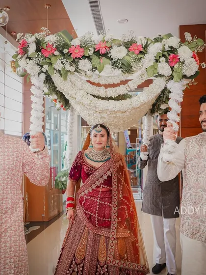 A classic bridal entry, elevated with a lush floral chaadar. The canopy of white flowers and pearls adds a touch of grace and tradition as the bride makes her way to the ceremony.