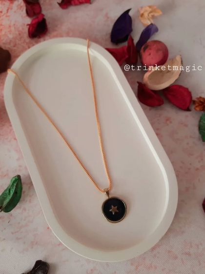 A dark and dreamy celestial necklace with a black enamel pendant featuring a single star. It's a chic and mysterious accessory.