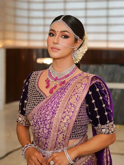 The quiet elegance of a traditional silk saree look. This makeup is powerful yet understated, featuring defined eyes and glowing skin to complement the rich purple and intricate details of the outfit.