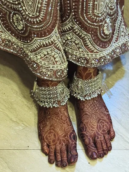 The beautiful henna stain on the bride's feet, perfectly complemented by her silver payal (anklets).