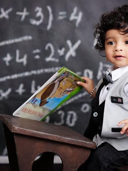 A creative "back to school" theme for a first birthday! This little scholar is posing at a tiny desk in front of a chalkboard.