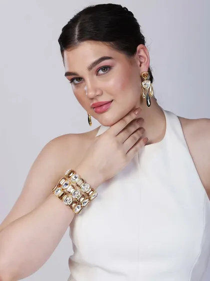 A close-up shot focusing on a model's elegant pose, showcasing a statement cuff bracelet and matching earrings, ideal for modern jewellery e-commerce listings.