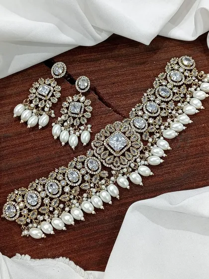 A classic choker with white polki stones and pearl drops, laid out to show its design.