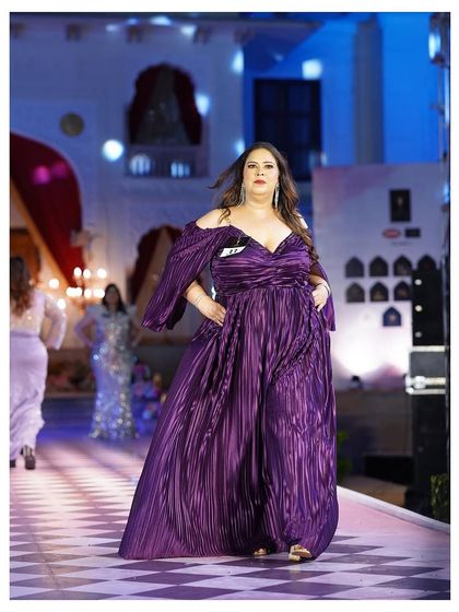 The purple plus-size gown from the front, showing the beautiful draping and the off-shoulder design.