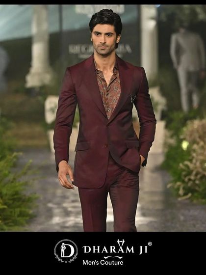 A model showcasing a deep maroon suit on the runway. The slim fit and rich color make it a versatile choice for a wedding guest or for a groom's reception look.