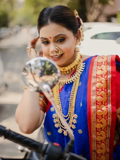 A fun and modern twist on a traditional photoshoot. The model, in full Gudi Padwa attire, checks her reflection in a motorcycle mirror, blending contemporary life with festive celebration.