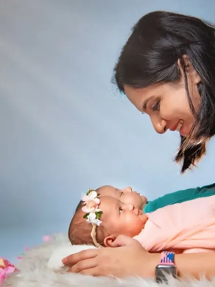 A precious moment as a mother gazes down at her smiling newborn twin. Capturing a newborn's smile is a rare treat, and this image radiates pure love and happiness.