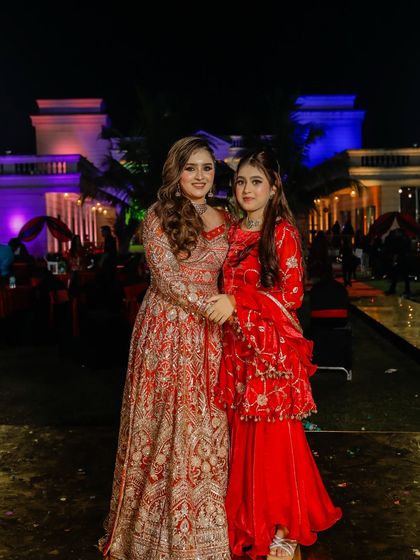 The bride with her sister at an outdoor evening event. Her glamorous look is perfect for celebrating with family.