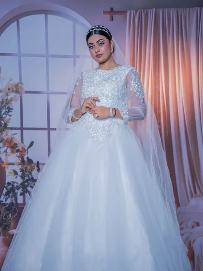 Your fairytale moment awaits. This beautiful white Christian bridal gown with delicate embroidery, a full tulle skirt, and a matching veil and tiara is available to rent for your special day.