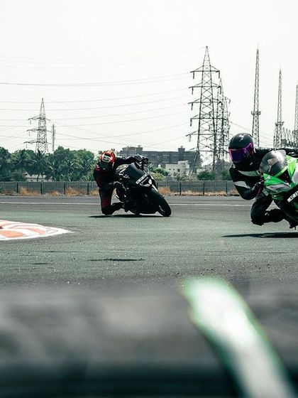 Two riders, one on a Kawasaki Ninja, cornering on the track.