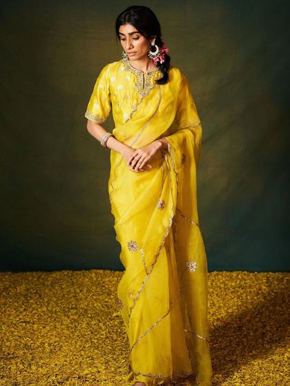 A model glows in a radiant yellow organza saree with delicate silver embroidery, perfect for a daytime wedding or festive event.