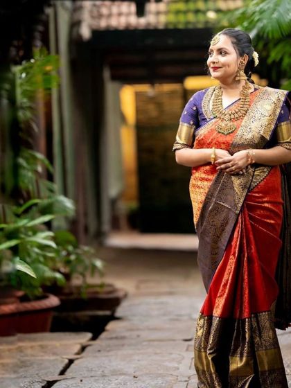 Client Apoorva radiates elegance in this luxurious bridal silk saree, featuring a striking contrast of deep red and blue, perfect for the modern South Indian bride.