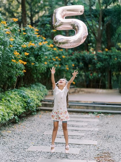A girl jumping for joy, trying to catch a "5" balloon. A perfect action shot for a fifth birthday celebration.