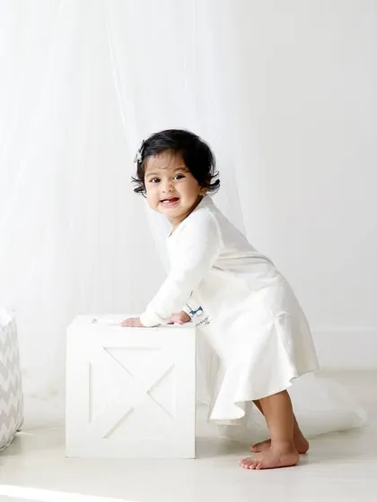 Taking her first wobbly steps while holding onto a prop. This is a huge milestone, and I'm always ready to capture these exciting moments.