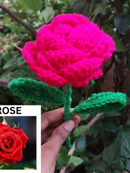 A vibrant pink crochet rose, held up against a natural green background. I can customize the colors to your liking.