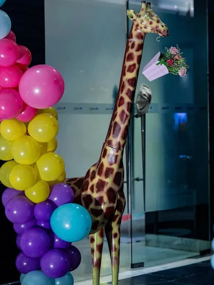 A life-sized giraffe prop decorated with a bouquet of flowers, standing next to a vibrant balloon arch. It's these quirky details that make my events unique and memorable.