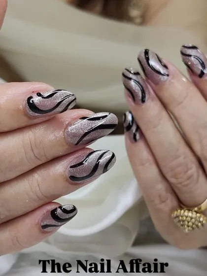 A trendy zebra-stripe design with black swirls over a shimmery silver base on almond-shaped nails.