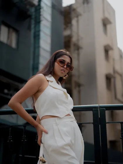 A profile shot of a model in a chic white outfit. The urban background is blurred, keeping the focus on her stylish look.