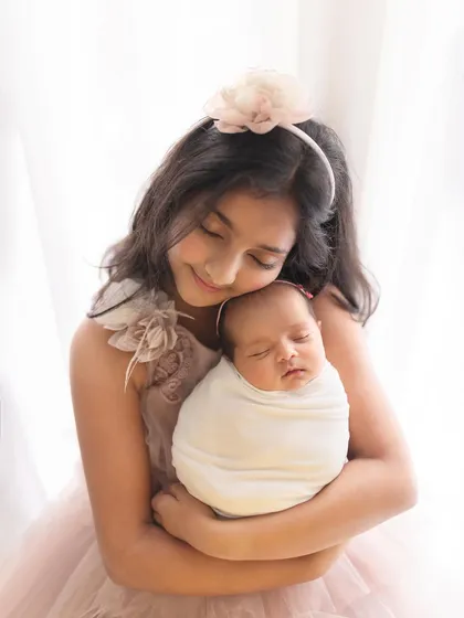 Another angle from this heartwarming sibling session, focusing on the gentle embrace and the peaceful sleep of the newborn.