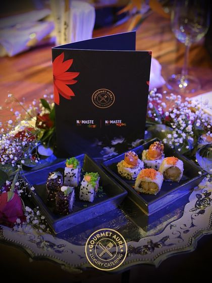 A beautiful tray of assorted sushi presented as part of an elegant table setting, surrounded by flowers. We integrate our food seamlessly into your event's decor.