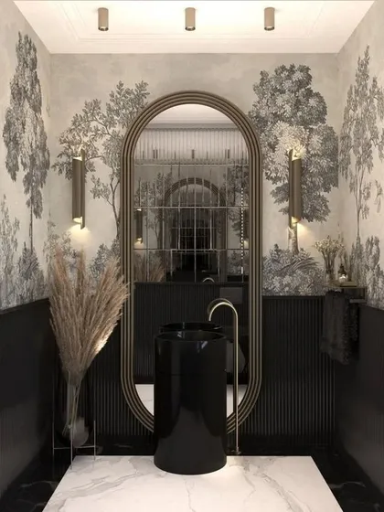 This powder room showcases how to create a big impact in a small space. The combination of a scenic wallpaper, a modern pedestal sink, and dramatic fluted wall paneling results in a memorable and highly stylized design.