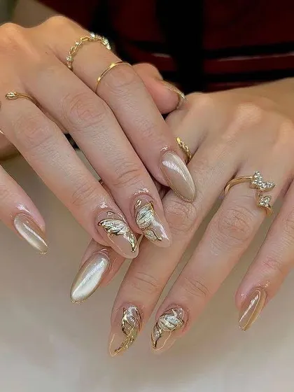 A sophisticated and trendy look. These almond-shaped extensions have a pearlescent, cat-eye base with delicate, 3D gold butterfly and metallic accents for a touch of elegance.