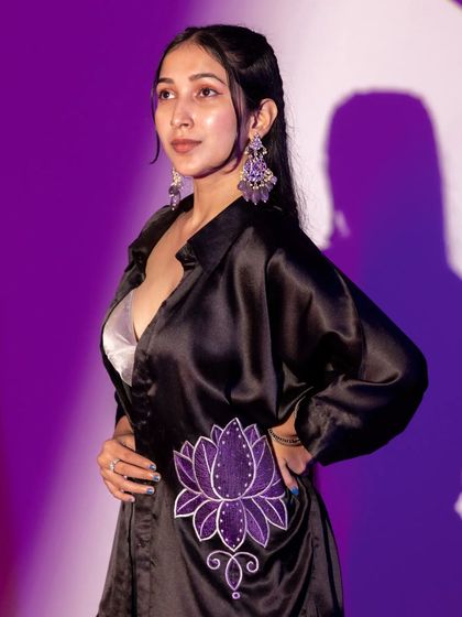 Using a purple background and spotlight, this shot focuses on the lotus embroidery of another designer shirt. The side profile and soft lighting create a sense of mystery and artistry.