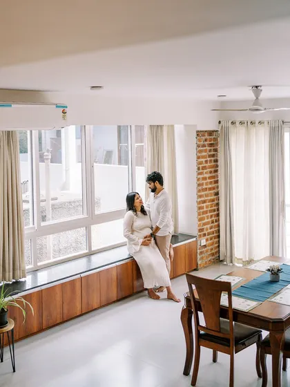 This wide shot showcases the couple in their beautiful, light-filled living space. It tells a larger story about their life and the home they are bringing their baby into.