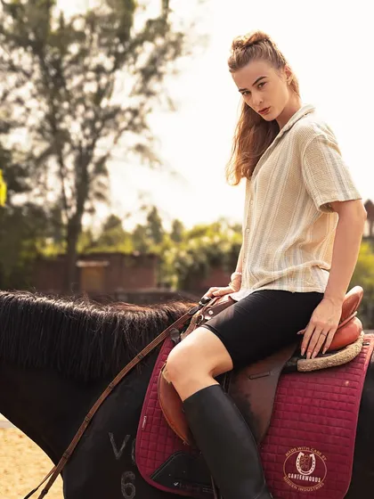 A full-body shot of a model seated on a horse, wearing riding boots. This image perfectly captures the aspirational equestrian lifestyle aesthetic.