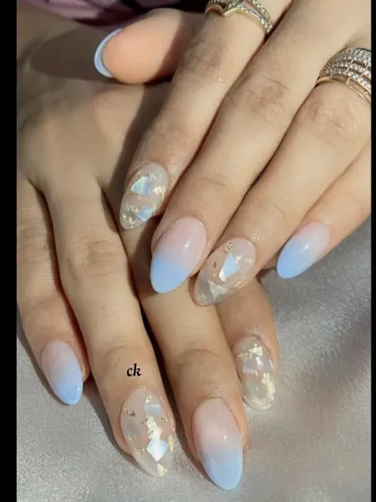 A dreamy blue ombré set, fading from a natural nude to a soft baby blue at the tips. The accent nails feature delicate seashell fragments for a touch of texture.