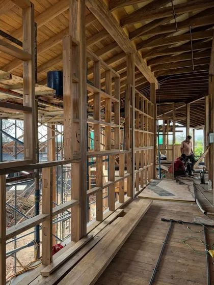 The interior timber framing of the farmhouse is revealed. This wooden skeleton provides the structure for the walls and roof, creating large, open volumes within the home.