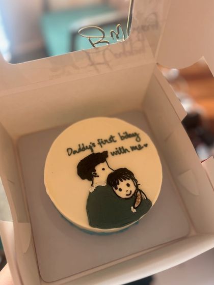 A heartwarming bento cake for a new dad, with a drawing of a father and child and the text "Daddy's first bday with me".