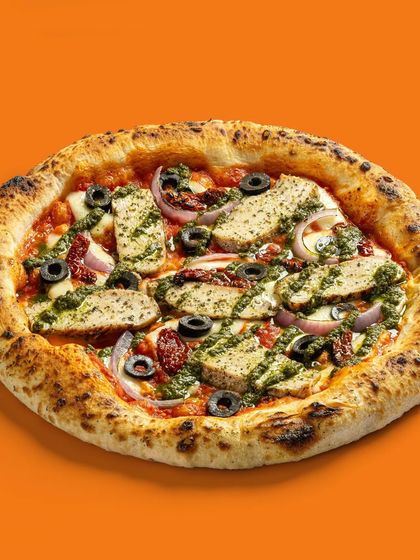 A pesto chicken pizza with sun-dried tomatoes and olives, offering a gourmet topping combination.