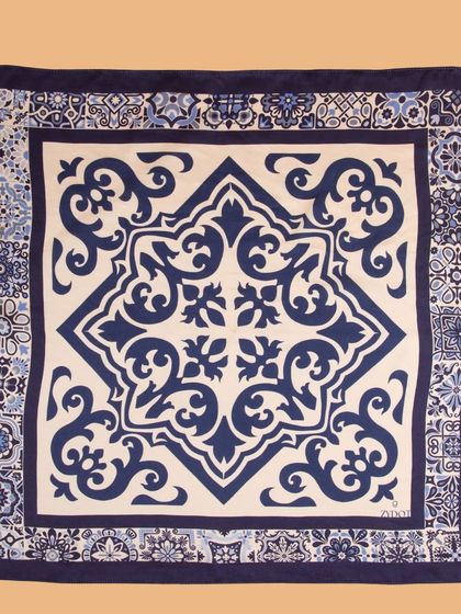 A flat-lay of a navy and white pocket square with an ornate tile-like pattern.