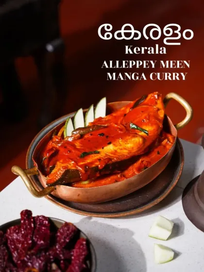 A vibrant red Alleppey Meen Manga Curry from Kerala, served in a traditional copper pot. The image, with its bold color and simple styling, speaks to the authentic and spicy flavors of the region.